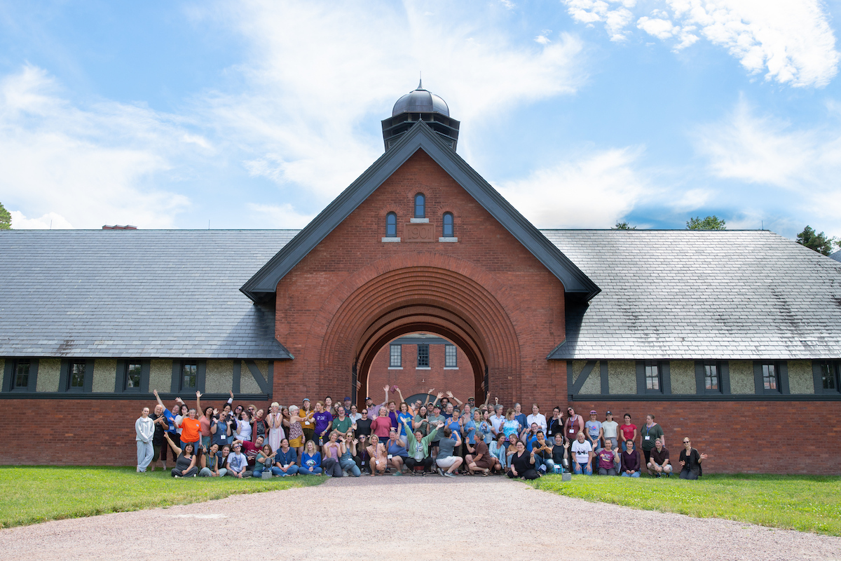 A large group of people gathered in front of the Shelburne Farms Coach Barn