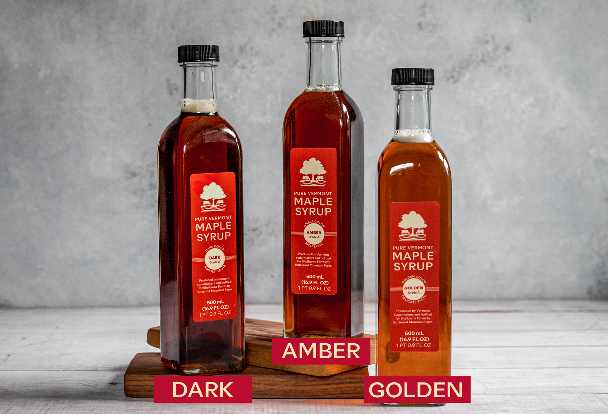 3 tall thin bottles of maple syrup of different grades 