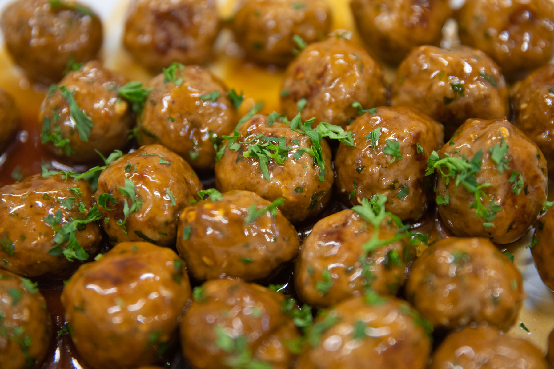 Close-up of glazed meatballs garnished with chopped parsley.
