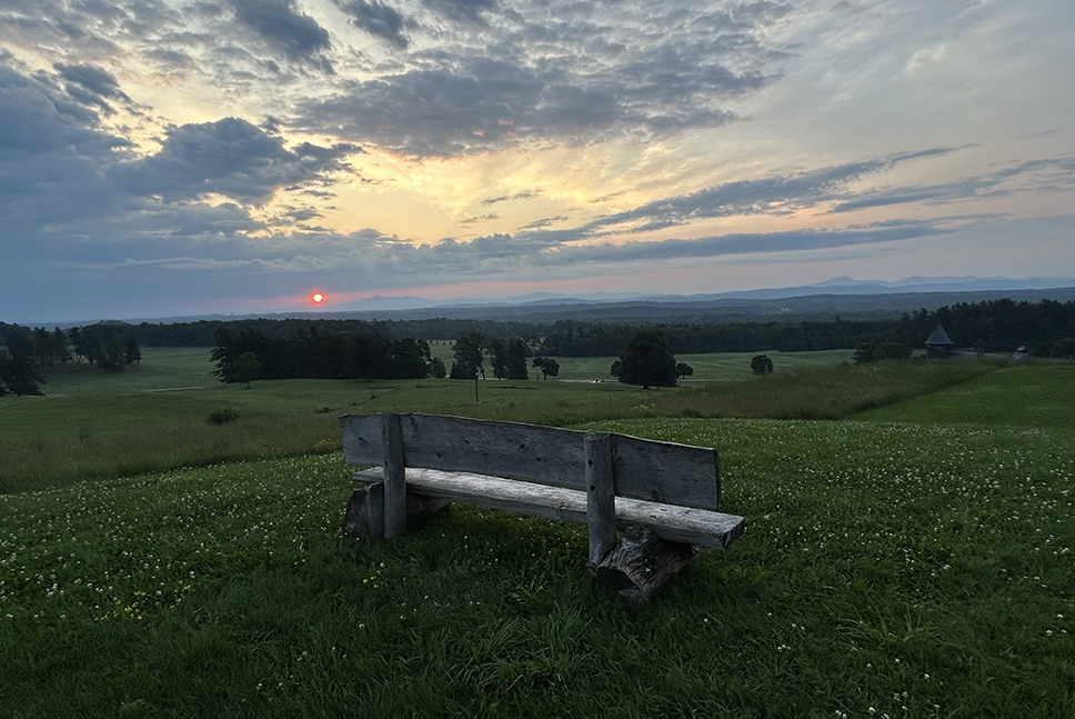 sunrise over mountains with bench in foreground