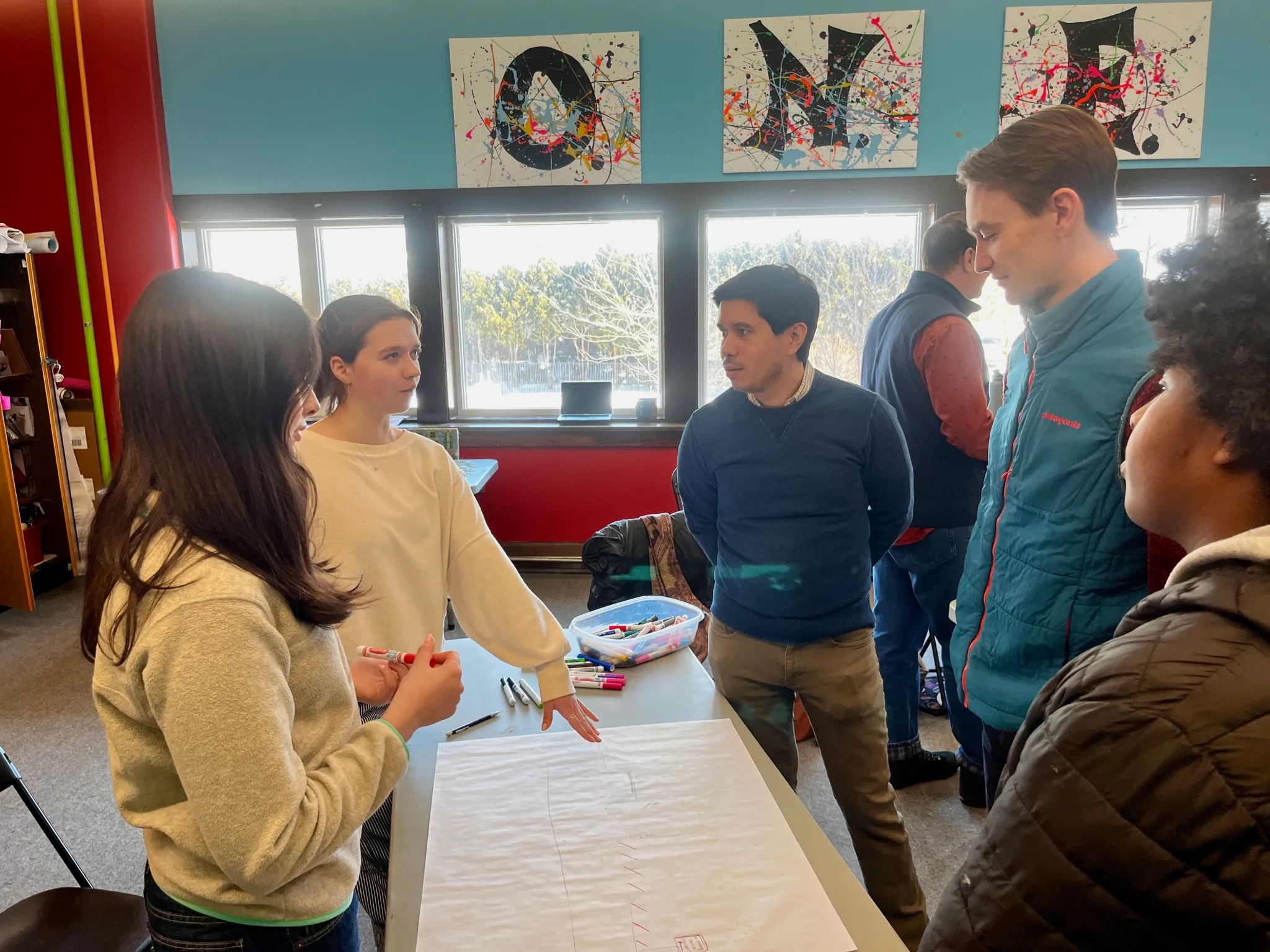 Young people and adults stand around a table in discussion