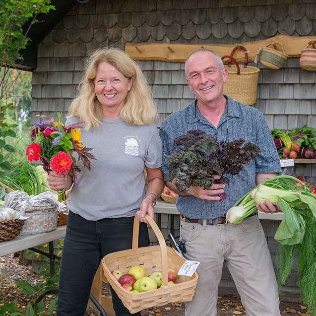 blond woman and man holding flowers and produce 