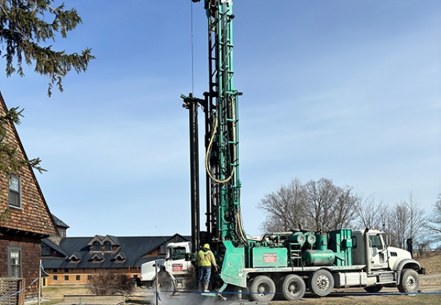 tall drill and truck drilling hole in the ground