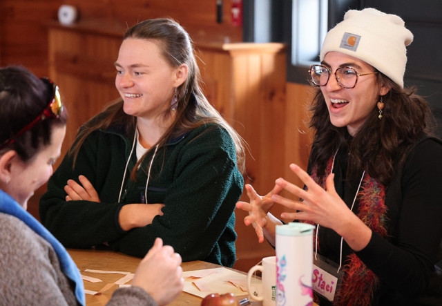 Three people have an animated discussion around a wood table