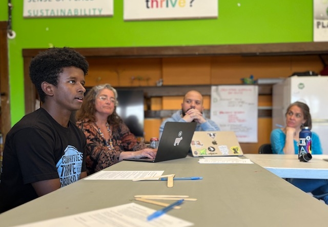 A young person and several adults talk around a classroom table