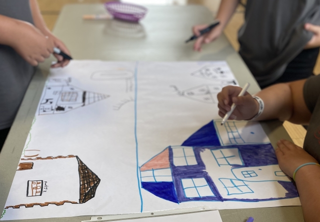 A large piece of paper depicting a house illustrated by young people