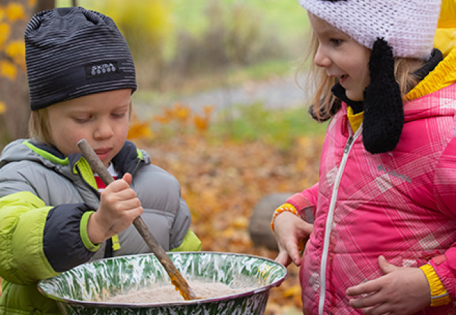 two young children in a fall forest, stirring pancake batter in a large bowl