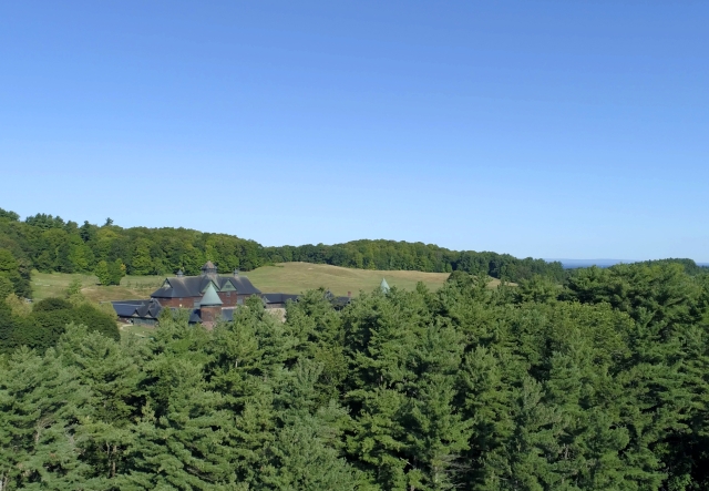 aerial of Farm barn in distance and evergreens in the front