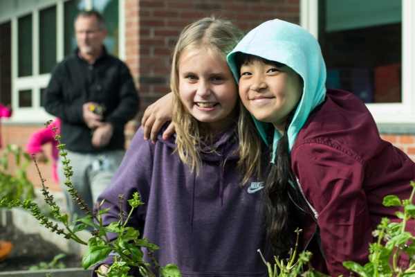 Two students harvest basil from a school garden in Burlington, Vermont.