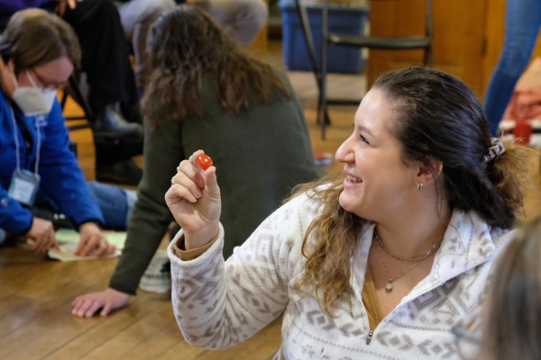 Educator smiles holding a cherry tomato