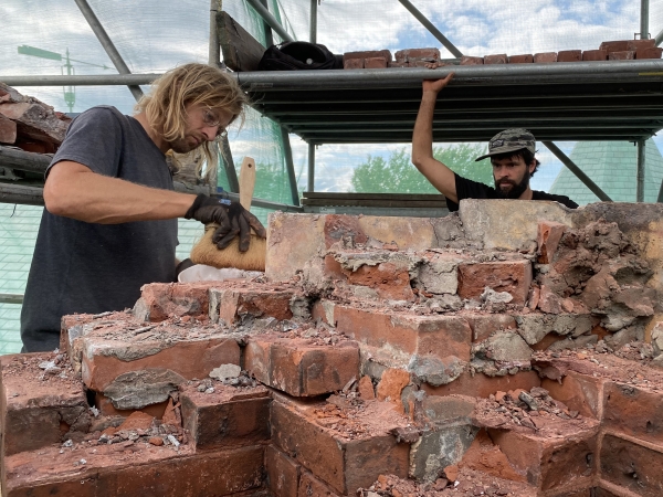 Men on staging cleaning and dismantling chimney bricks.