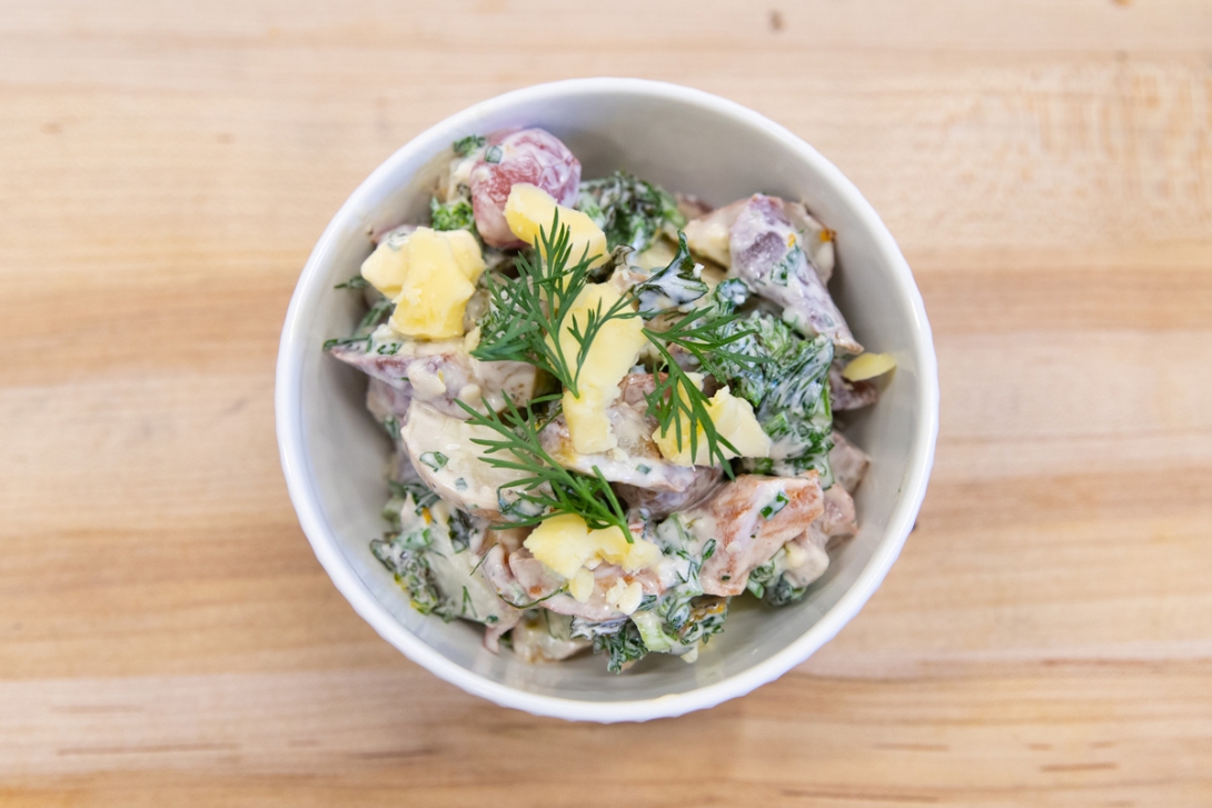 A bowl of potato salad with mixed herbs.